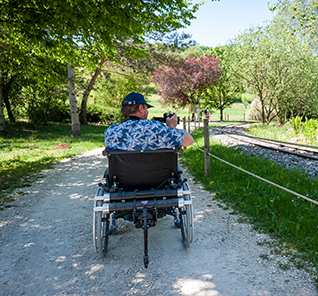 Homme photographiant un paysage en fauteuil roulant avec une double motorisation Maxi Minotor 2.1 de Benoit Systemes.