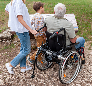 Homme qui se balade en famille dans un fauteuil roulant avec une motorisation Pousseur 2.1 de Benoit Systemes.