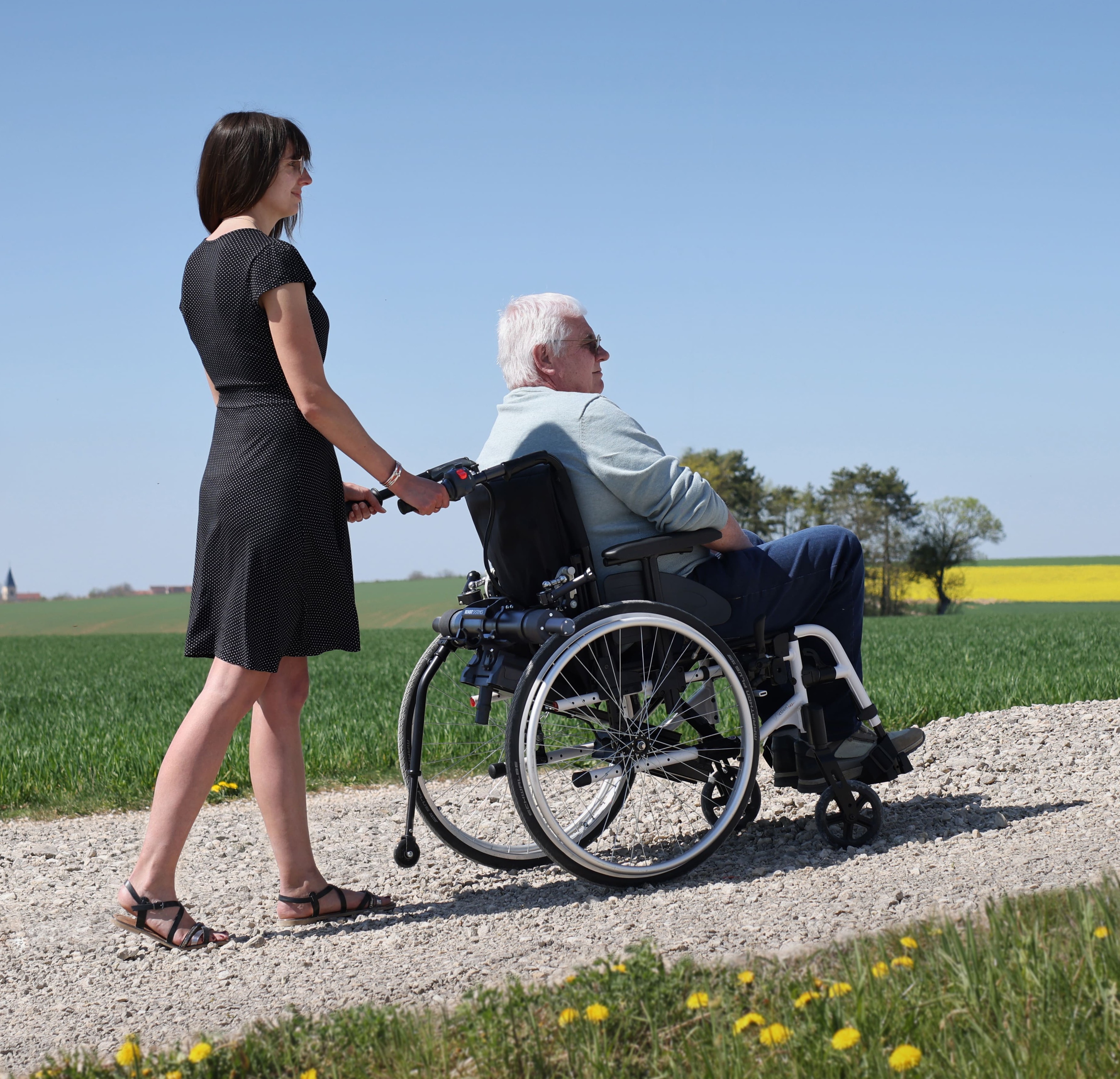 Homme qui se balade en famille dans un fauteuil roulant avec une motorisation Pousseur 2.1 de Benoit Systemes.